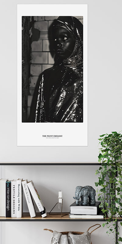A poster on a wall, above a modern bookshelf, of a nun wearing a fabulous shiny sequin-covered outfit with a textured subway tiled wall background, waiting for the subway, circa 80sm sepia tone. The Print Embassy logo is placed below the image.