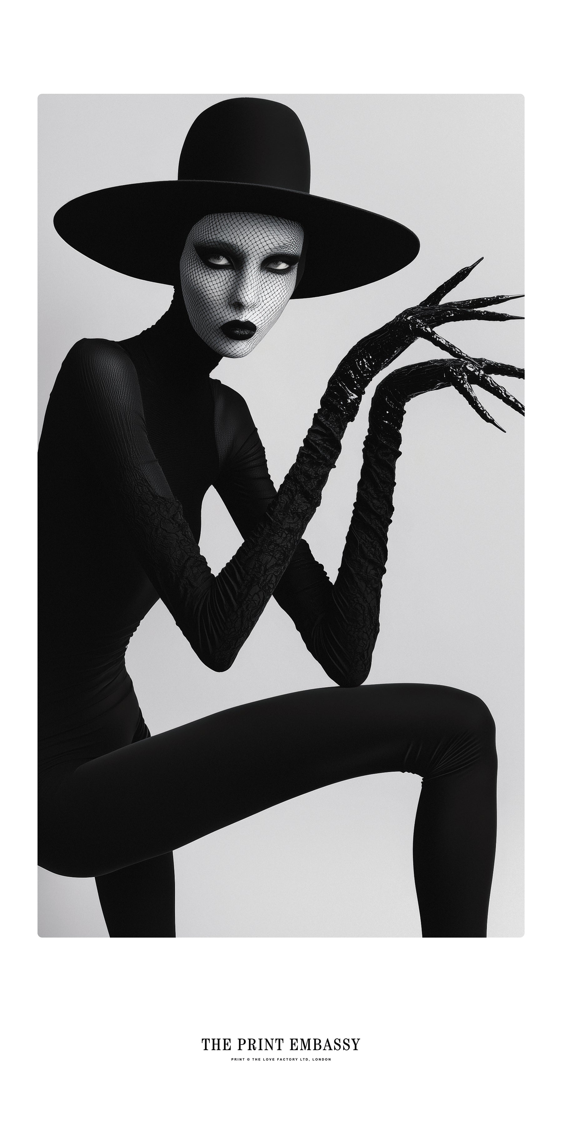 A statement black and white art piece of a person in a black outfit and large Boy George styled hat, the model is wearing long, spooky clawed gloves. It could be a still from a Marilyn Manson music video.