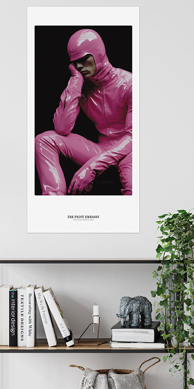 A person wearing a pink outfit with a black background, the large oversized print is hanging on a wall above a shelf.