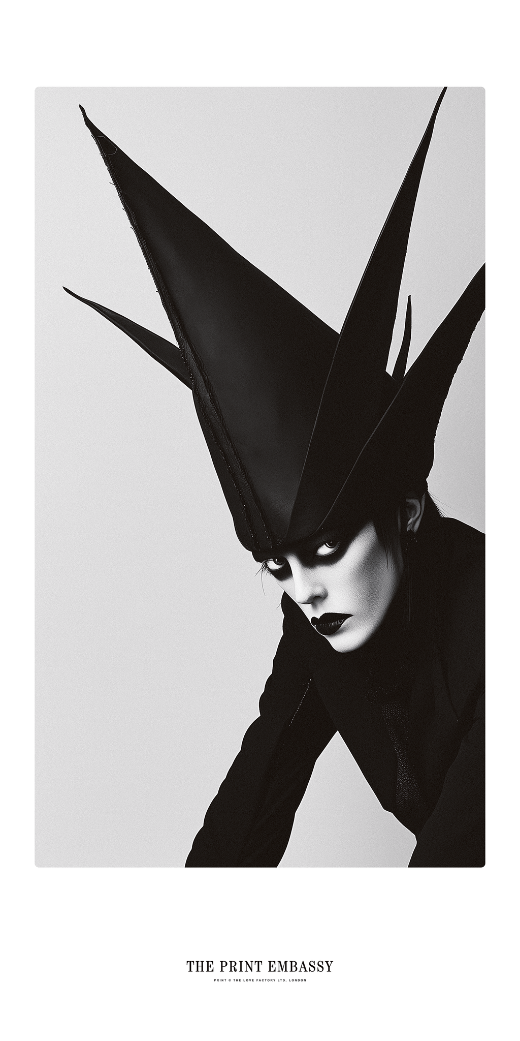 A person wearing a high, pointed black hat against a light gray background, this could be a screengrab from a Marilyn Manson music video, it's fun and creepy all at once. One things for sure, this guy has style.