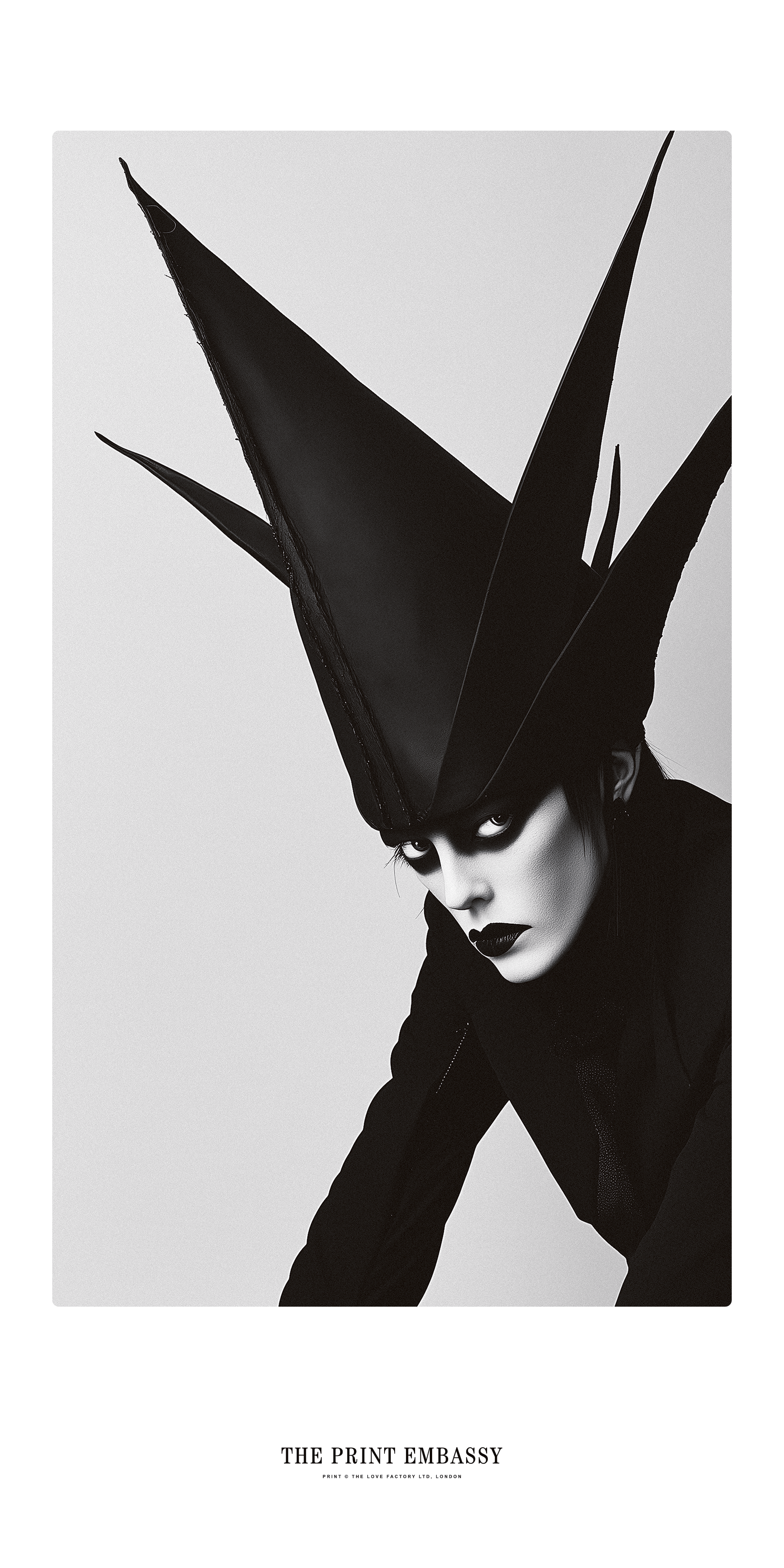 A person wearing a high, pointed black hat against a light gray background, this could be a screengrab from a Marilyn Manson music video, it's fun and creepy all at once. One things for sure, this guy has style.