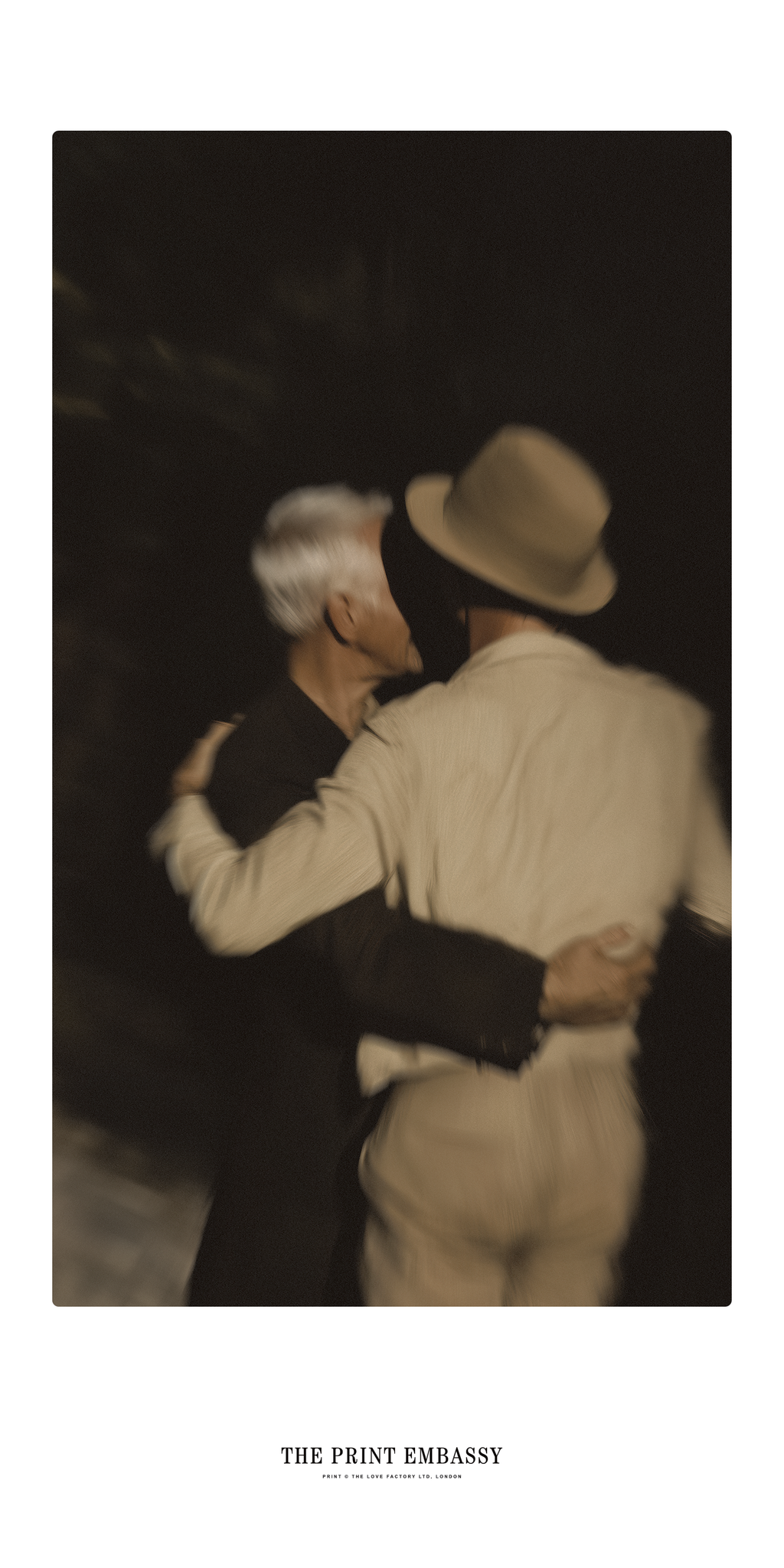 A romantic blurry shot of 2 men dancing closely in a nighttime outdoor setting, with 'The Print Embassy' branding at the bottom.