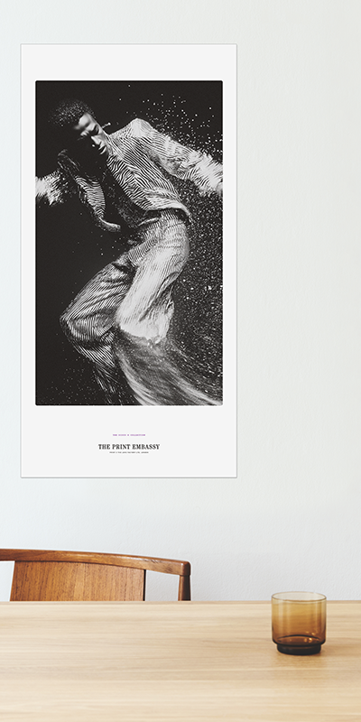 Framed black and white artwork of a person in a dynamic pose on a wall above a wooden table.