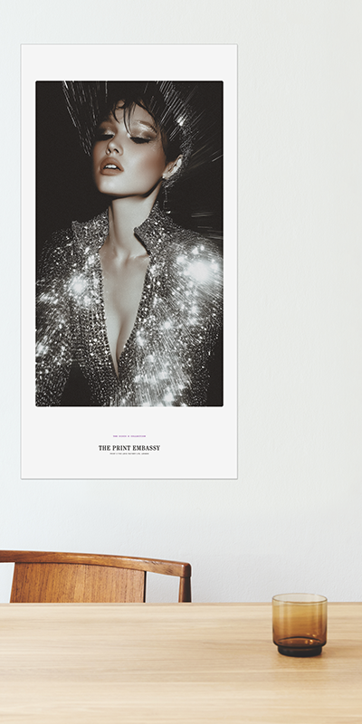 Poster of a woman in a sparkly outfit on a wall above a wooden table with a glass.