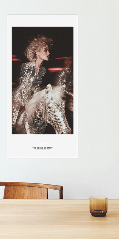 Framed poster of a woman in a sparkly outfit on a wall above a wooden table with a glass.