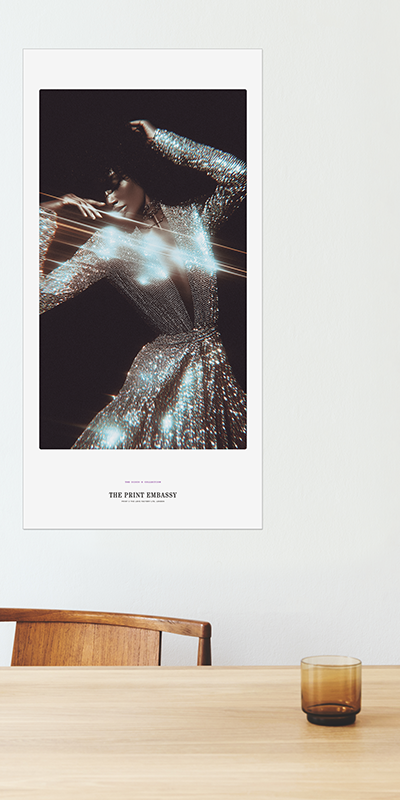 Poster of a woman in a sparkling outfit on a wall above a table with a glass.